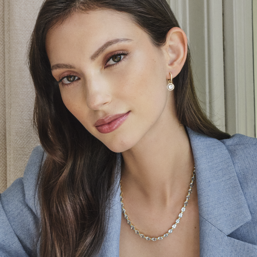Woman wearing a necklace and earring with a neutral background